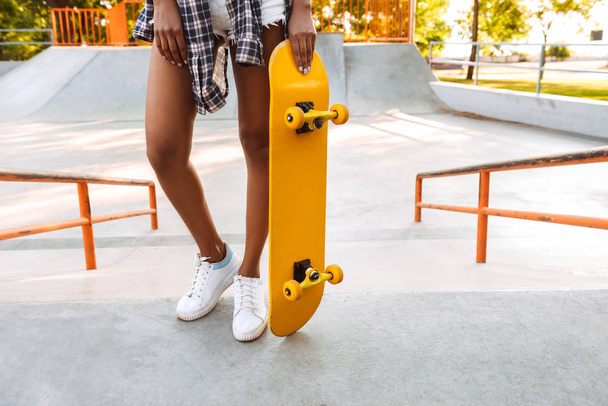 Cropped photo of young african woman walking outdoors with skateboard. - Foto, Imagem
