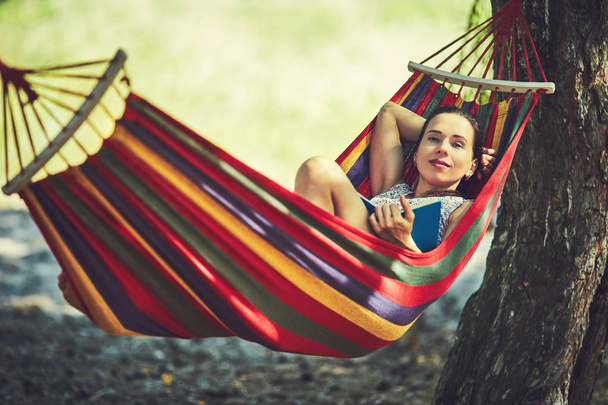 Woman resting on a hammock reading a book - Photo, Image