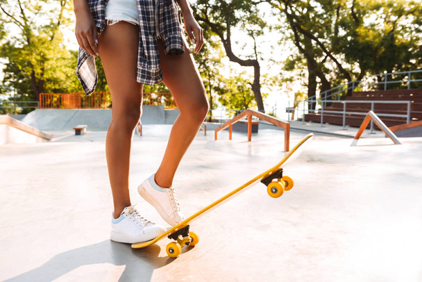 Cropped image of a young african girl standing with skateboard at the park - Fotó, kép
