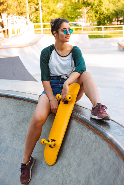 Photo of young happy cheerful woman walking outdoors with skateboard. - Foto, Imagen