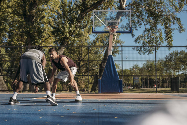 Два красивых мужчины играют в баскетбол на открытом воздухе
. - Фото, изображение