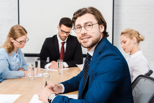 красивый молодой бизнесмен, сидящий в конференц-зале с коллегами во время разговора
 - Фото, изображение