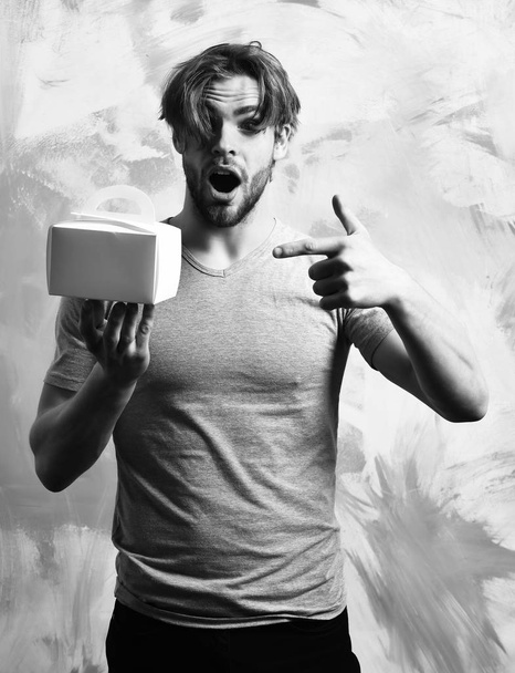 holding meal box or container on colorful studio background. Caucasian bearded sexy macho man holding meal box - Fotografie, Obrázek