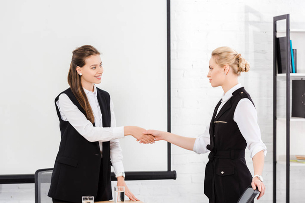 attractive young businesswomen shaking hands at conference hall - Фото, изображение
