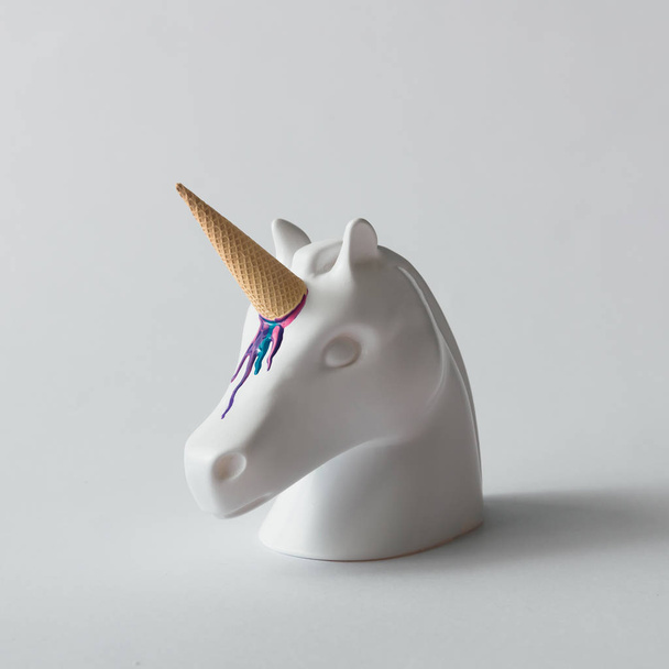 Wit geschilderd unicorn hoofd met kleurrijk ijs hoorn op helder witte achtergrond. Minimal art fantasie concept. Zomer fairytale. - Foto, afbeelding