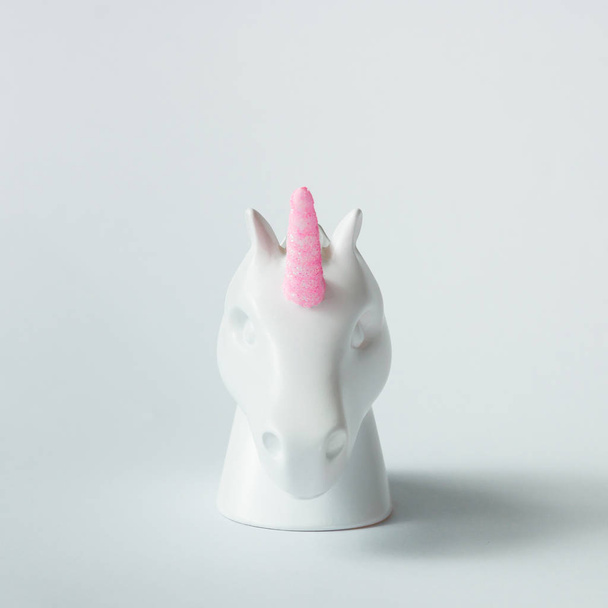 White painted unicorn head with pink horn on bright white background. Minimal art fantasy concept. - Foto, afbeelding