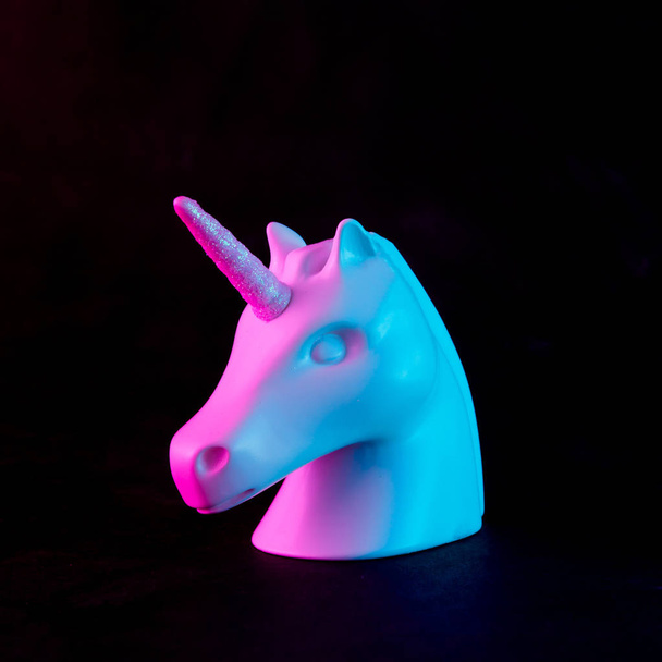Testa di unicorno verniciato bianco in audaci colori rosa e blu al neon su sfondo scuro. Concetto di fantasia arte minimale
. - Foto, immagini