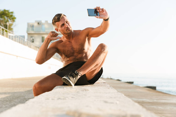 Photo of handsome strong mature sportsman take selfie pointing to himself on the beach. - Фото, изображение