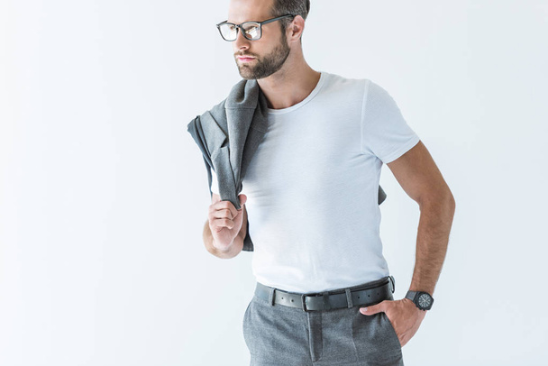 elegantní muž v brýlích pózuje s bundou na rameni, izolované na bílém - Fotografie, Obrázek