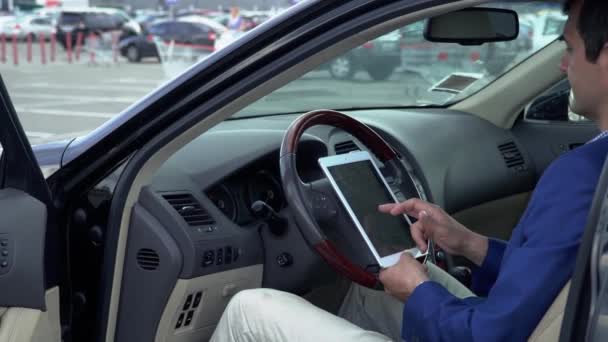 Business man sitting in the car with a tablet - Video