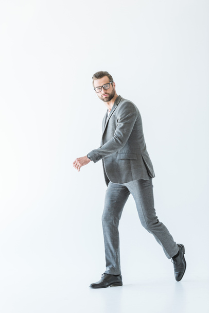 stylish businessman walking in gray formal wear, isolated on white - Fotoğraf, Görsel