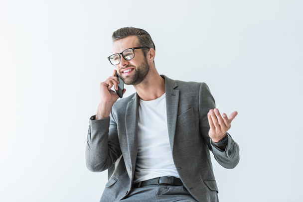 hymyilevä liikemies harmaassa takissa elehtii ja puhuu älypuhelimella, eristetty valkoisella
 - Valokuva, kuva