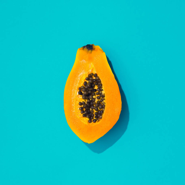 Creative tropical layout with papaya and blue vivid paper. Abstract food art background. Minimal summer concept. Flat lay. - Фото, изображение