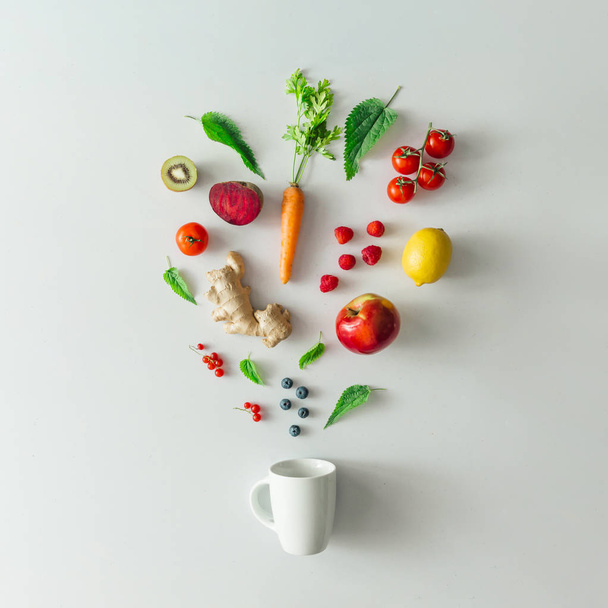 Kreatives Essenslayout mit Obst, Gemüse und Blättern auf hellem Marmortischhintergrund mit Teetasse. minimales gesundes Getränkekonzept. flache Lage. - Foto, Bild