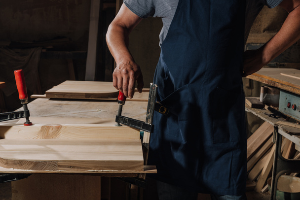vista parcial del carpintero de pie akimbo en taller de madera
 - Foto, Imagen