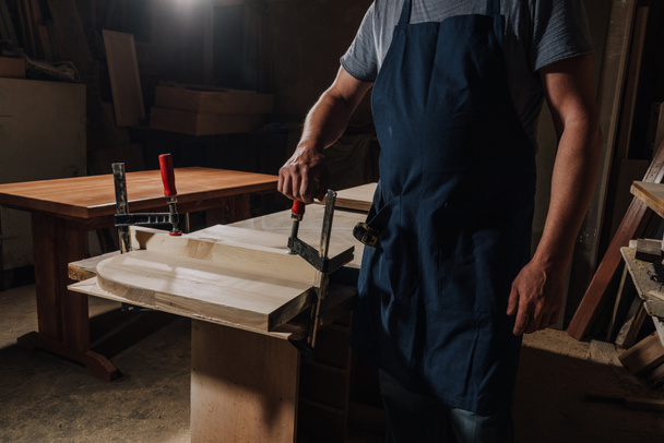 vista parcial del carpintero de pie en el taller de madera
 - Foto, Imagen