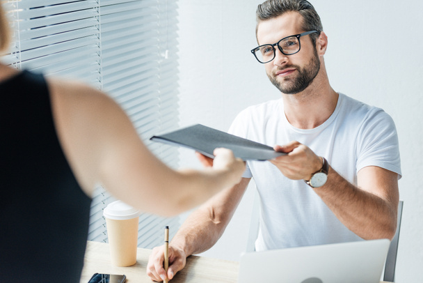 handsome businessman giving documents to colleague in modern office - Photo, Image
