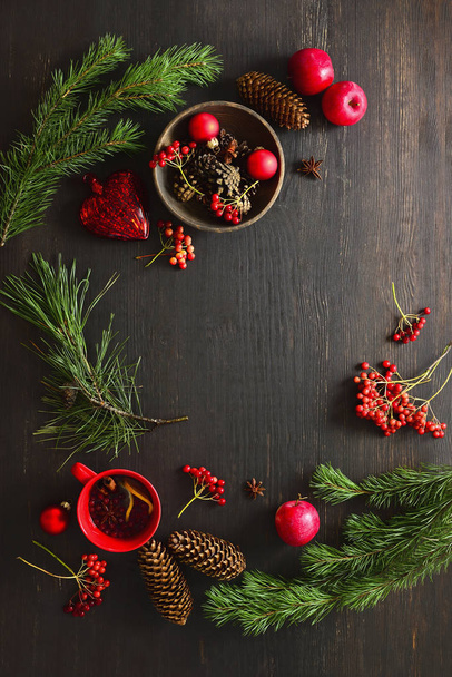 Christmas natural decor stuff on moody rustic table top ready for setting a dinner table, cup of winter warmer standing below, cones, fruits and winter berries around the center - Photo, Image