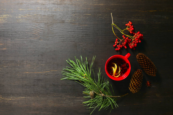 Winter wärmender Tee aus natürlichen heilenden Inhaltsstoffen in roter Tasse steht auf stimmungsvollem rustikalem Hintergrund, Blick von oben - Foto, Bild