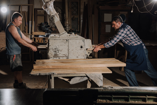 carpinteros trabajando con tablones de madera en taller de madera
 - Foto, Imagen