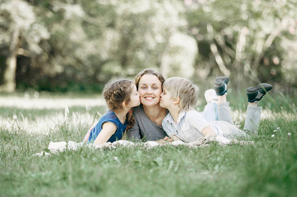 brother and sister kissing mom on the lawn in the Park - Фото, зображення