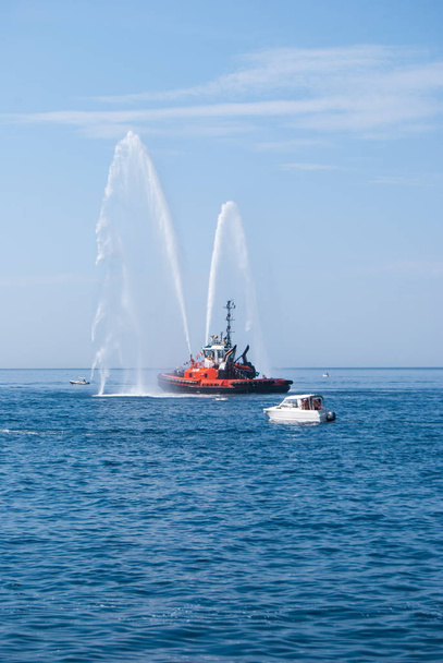 Twee stralen zeewater door een brandweerwagen van een boot brandweerlieden rood gespoten - Foto, afbeelding