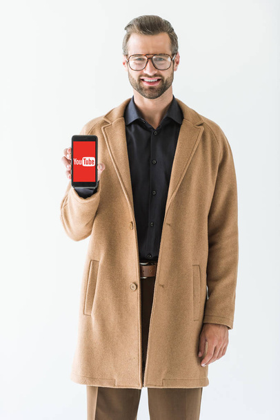 bearded smiling man presenting smartphone with youtube appliance, isolated on white - Valokuva, kuva
