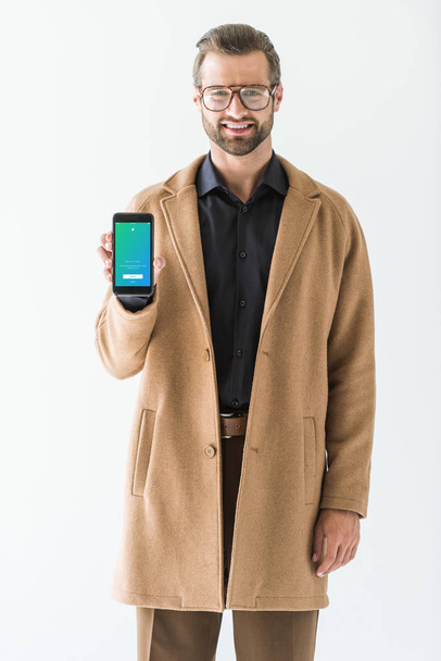 homem bonito em roupa de outono apresentando smartphone com aparelho twitter, isolado em branco
 - Foto, Imagem