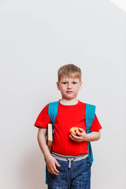 happy first grader in the red t-shirt and backpack looking at camera on white background - Фото, зображення