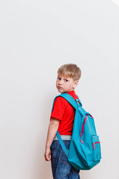 first grader in the red t-shirt and backpack looking at camera on white background - Valokuva, kuva