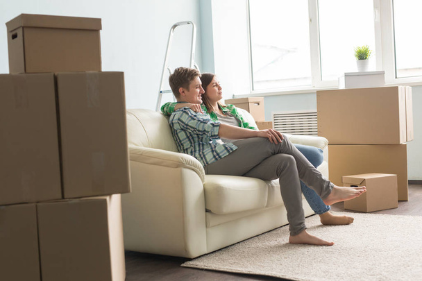 Umzug, Neues, Menschen-Konzept - glückliches verliebtes Paar sitzt in leerer Wohnung zwischen Kisten und träumt von der Zukunft - Foto, Bild