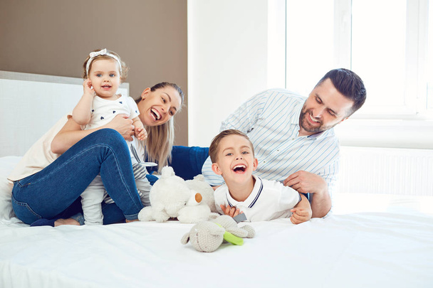 Happy family  playing lying on the bed in the bedroom. - Фото, зображення