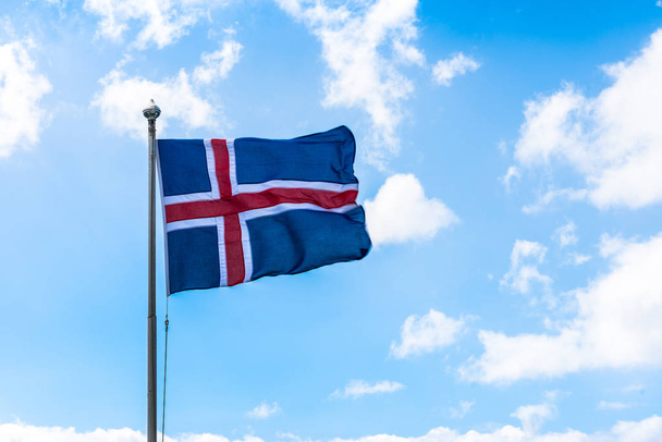 Icelandic flag blowing in the wind with White clouds and blue sky. - Foto, imagen