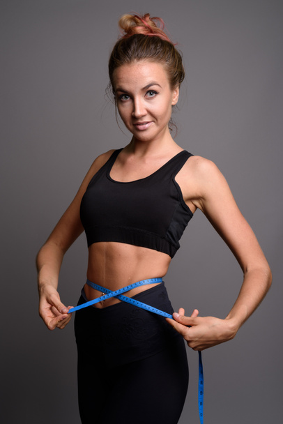 Young beautiful woman ready for gym against gray background - Fotografie, Obrázek