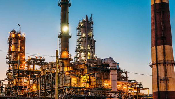 Fabryki w zachód słońca, gorzelnia zbiorników i rurociągów stalowych, nowoczesne technologie petrochemicznego lub zakład przemysłowy rafinerii ropy naftowej - Zdjęcie, obraz