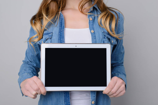 Kobieta w jeans koszula gospodarstwa cyfrowy tabeli z puste czarny ekran dla tekstu. on jest na białym tle na szarym tle - Zdjęcie, obraz