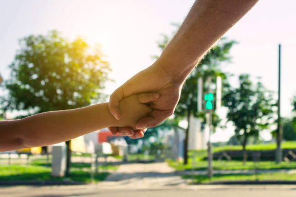 A biztonsági koncepció a gyermek. Az Atya tartja a gyermek kezét, a gyalogos átkelés. A háttérben, egy homályos forgalomirányító - Fotó, kép