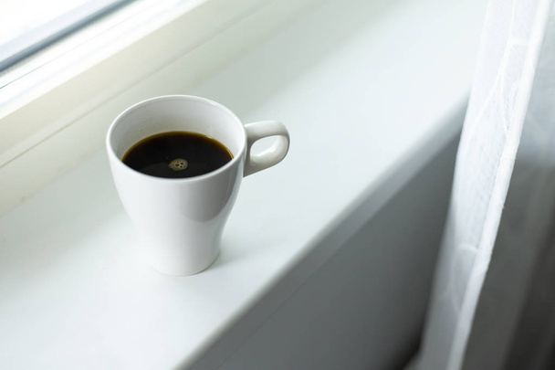 A cup of coffee on the windowsill. Big window. Scandinavian style. Copy space - Zdjęcie, obraz