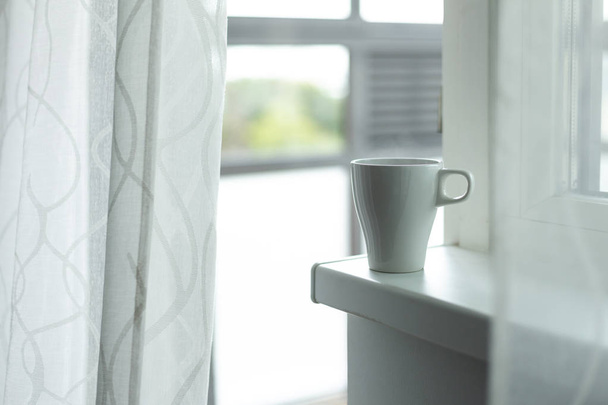 A cup of coffee on the windowsill. Big window. Scandinavian style. Copy space - Fotó, kép