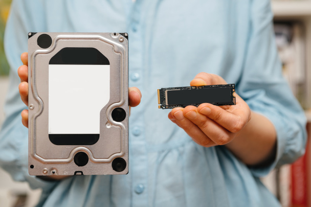 Woman hands holding new NVME PCIE SSD hard drive disk with high read and write speed with bigh old HDD drive - Photo, Image