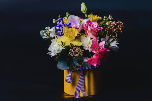 gekleurde bloemboeket in mand op donkere achtergrond - Foto, afbeelding