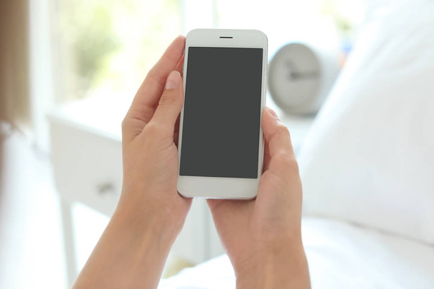 Woman holding smartphone with blank screen on blurred background. Mockup for design - Fotografie, Obrázek