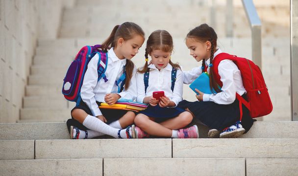 Ευτυχισμένα παιδιά κορίτσια φίλες μαθήτριες μαθητή δημοτικού σχολείου με ένα smartphon - Φωτογραφία, εικόνα