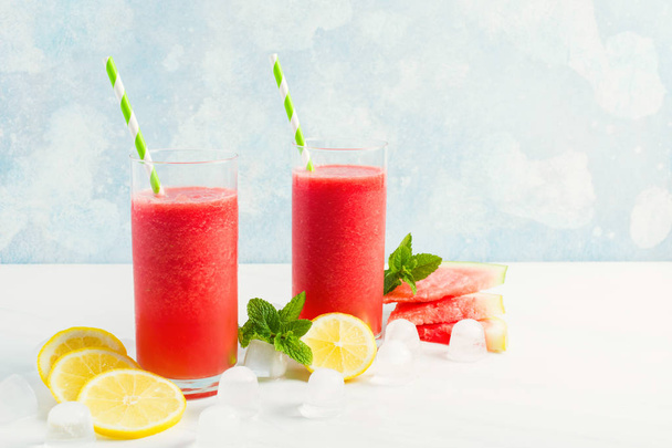 Summer watermelon drink in glasses with lemon and mint on blue background - Photo, image