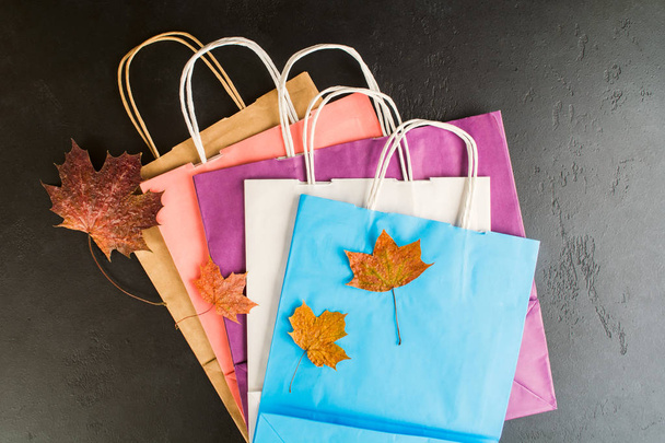 Colorful paper bags for shoping with autumn foliage, flat lay style - Foto, afbeelding