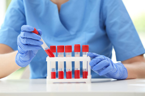Naukowiec gospodarstwa probówki z próbki krwi przy stole w laboratorium - Zdjęcie, obraz
