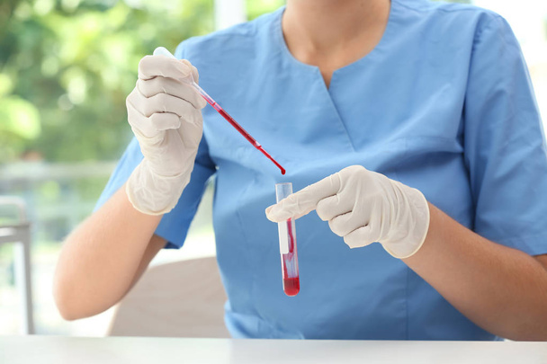 Scientist dripping blood into test tube in laboratory - Zdjęcie, obraz