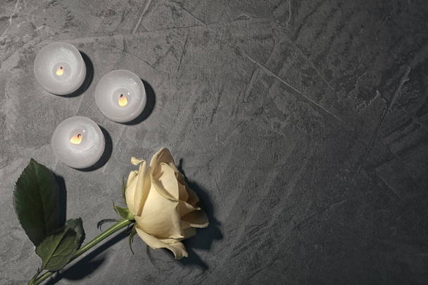 Beautiful white rose and candles on grey background, top view. Funeral symbol - Photo, Image