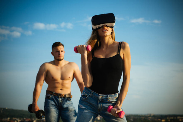 VR simulator for fitness. Woman wear VR glasses build muscles with dumbbells. VR stimulator for better result. VR as training tool. Enjoy new reality - 写真・画像