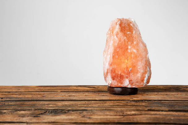 Himalayan salt lamp on table against light background - Zdjęcie, obraz